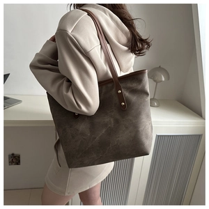 Détail d'un grand sac cabas marron avec de fines bandoulières porté par un mannequin en tenue