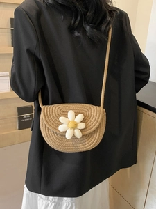 Handmade straw saddle bag with a white daisy flower on a woven crossbody shoulder strap