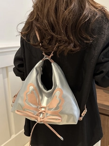 Mochila plateada metalizada con parche de lazo rosa y correas ajustables de moda
