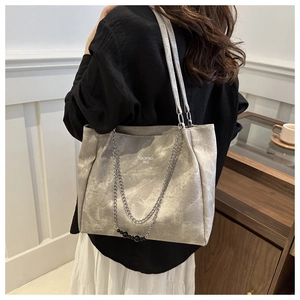 Detail of grey tote bag with marble texture and silver chain strap on model