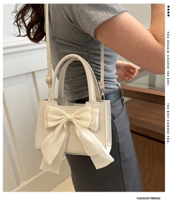 Dettaglio di una mini borsa bianca con fiocco in rete indossata a tracolla
