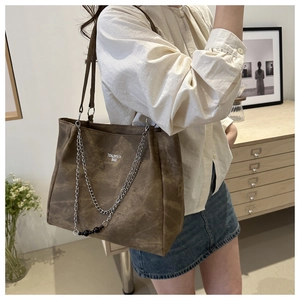 Detail of vintage brown tote bag with metal chain strap and decorative black beads