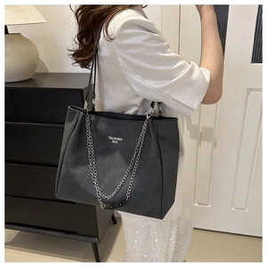 Close-up of black matte leather tote bag with silver chain detail and tidal typography