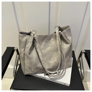 Detail of grey vintage texture tote bag with leather strap and decorative metal chain