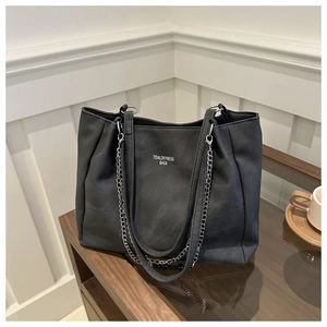 Detail view of large black tote bag with silver chain strap and matte texture surface