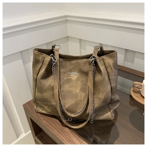 Close-up of brown vintage tote bag with metal chain, beads, and white brand logo