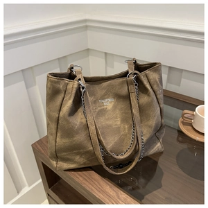 Detail of a brown large capacity tote bag featuring silver chain and white logo text