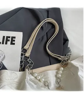 Detail of satin tote bag with butterfly jacquard texture, pearl chain and metal accents