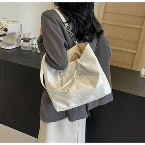Detailed texture of white tote bag featuring butterfly jacquard and pearl chain charm