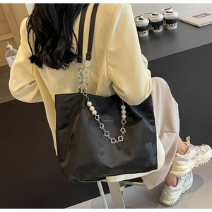 Detail of black butterfly print tote bag with silver chain and white pearl charms