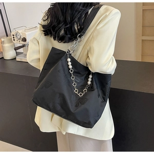 Detail of black nylon tote bag with butterfly pattern and decorative pearl chain