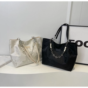 Detail of tote bag with butterfly jacquard texture, pearl handles and fashion label