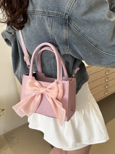 Mini borsa a tracolla rosa con grande fiocco in organza mostrata su modella