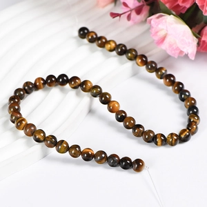 Natural tiger eye stone beads on white textured background with cat eye effect