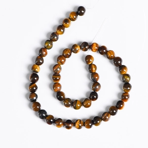 Natural yellow tiger eye stone round beads arranged in a spiral on white background