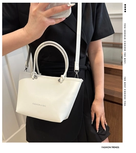 Detailed view of a white minimalist bucket bag with thin straps and round top handles