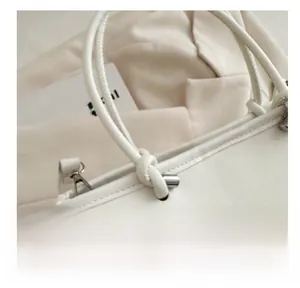 Detail of high-quality stitching and metal hardware on cream leather bucket bag