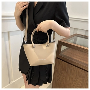Close-up of beige PU leather bucket bag with FASHION & BAG print and adjustable strap
