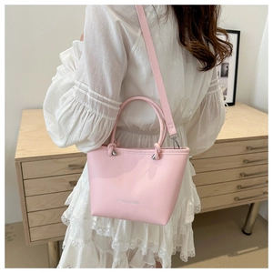 Lifestyle shot of pink PU leather tote bag worn as crossbody in a minimalist interior