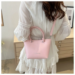 Pink minimalist bucket bag with FASHION & BAG lettering worn as a crossbody shoulder bag