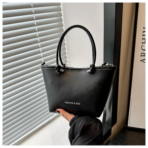 Close-up of knotted handle detail and white brand lettering on a black leather handbag