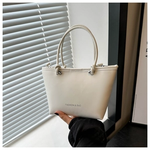 Detail of white fashion tote bag with silver metal rings and smooth leather texture