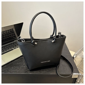 Detail of black leather bucket bag with knot handle and Fashion & Bag text on desk