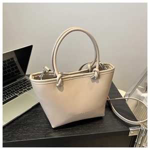 Close-up of beige leather bucket bag with top handles and adjustable crossbody strap