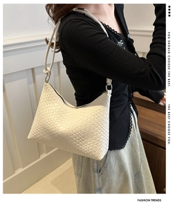 Detail view of white woven shoulder bag with checkered texture and silver ring hardware