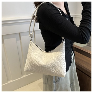Detailed close-up of a white woven faux leather hobo bag on a model's shoulder