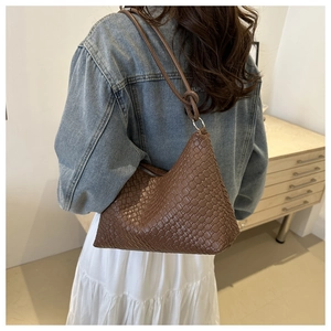 Detail shot of brown woven leather hobo bag with a knotted strap and smooth triangular shape