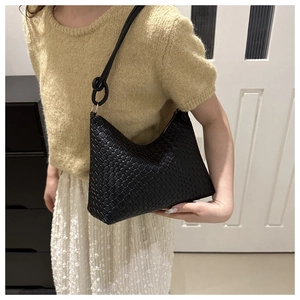 Détail d'un sac porté épaule tressé noir avec bandoulière nouée et finition texturée