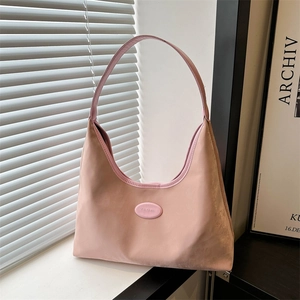 Minimalist pink suede hobo shoulder bag with logo on a sunny windowsill