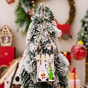 Detail of wooden Christmas gnome sledge ornament hanging on a snowy tree branch