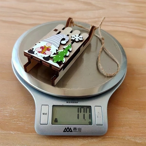 Detail view of a 11.1g wooden Christmas gnome sled ornament on a digital kitchen scale