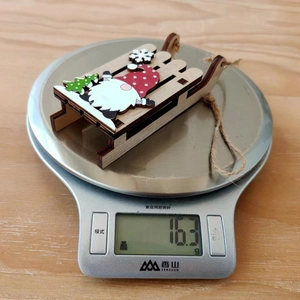 Macro view of Christmas wooden sledge pendant weighing 16.3g on a scale for festive decor