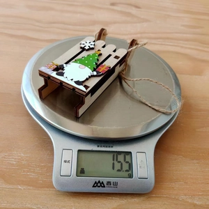 Weight measurement of a wooden Christmas gnome sleigh ornament showing 15.5g on a scale