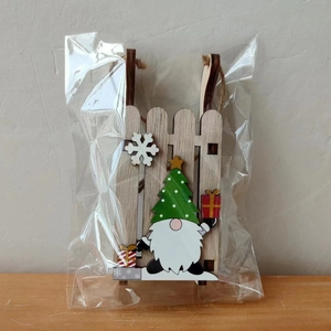Detail of wooden sledge ornament with gnome and snowflake in clear plastic packaging