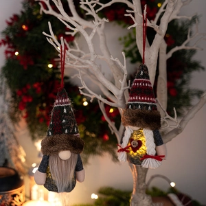 Nahaufnahme leuchtender LED Weihnachtswichtel an weißen Zweigen mit festlichen Beeren