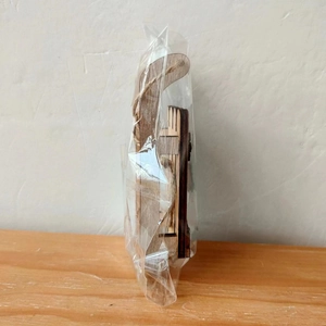Close-up of a wooden gnome sled ornament with natural grain and hemp rope loop in packaging