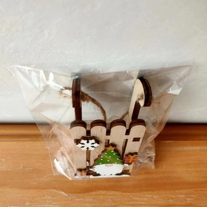 Detail of wooden Christmas gnome sledge ornament with snowflake in plastic packaging