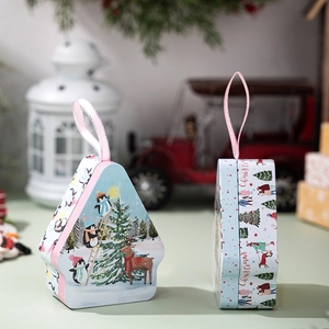 Macro shot of house-shaped Christmas tin boxes with festive penguin and reindeer illustrations