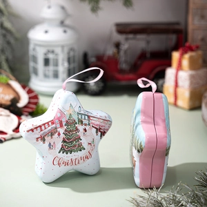 Close-up of star-shaped tin Christmas candy box with hanging ribbon and festive scene