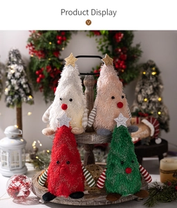 Close-up of plush Christmas tree dolls with sequin stars on a rustic wooden tray
