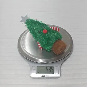 Detail view of a plush Christmas tree doll on a digital scale showing a weight of 43.5g