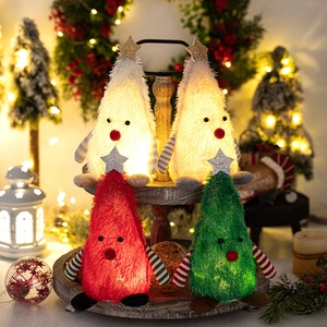 Close-up of four glowing plush Christmas tree figurines on a vintage wooden tray