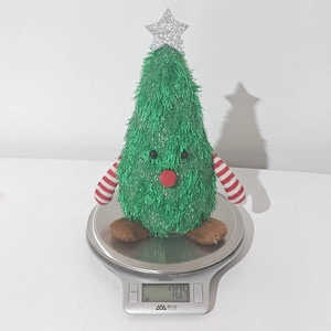 Detailed view of green plush Christmas tree doll showing weight of 110.4g on electronic scale