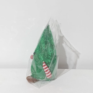 Detail view of a plush Christmas tree doll with green fur and a striped scarf in packaging