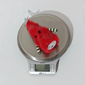 Close-up of a lightweight 18.6g glowing plush Christmas tree ornament on a scale