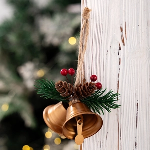 Detail of Christmas bell hanging with pine cones, red berries and jute rope on wood